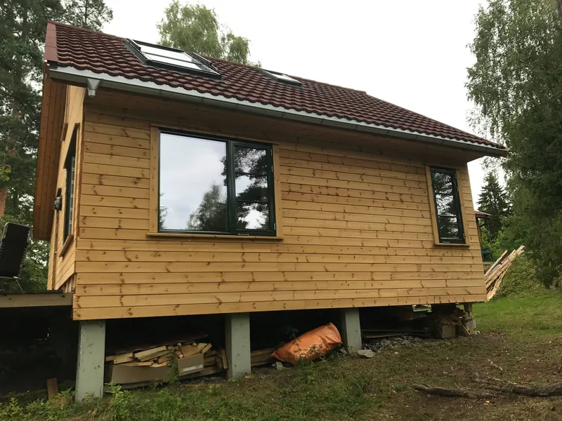 Trehus på pilarer med nytt tak og takvinduer